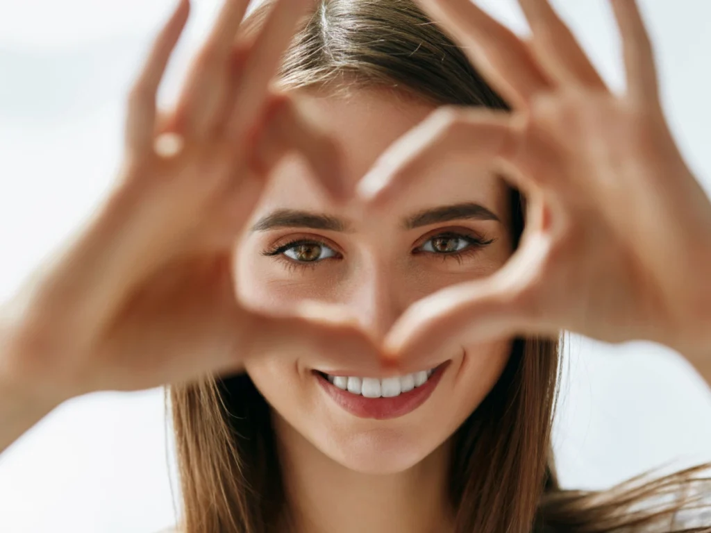 woman with heart hands over her eyes